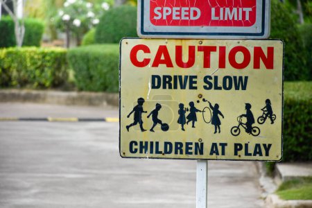 Sign caution speed limit drive slow children at play on yellow background at park in evening sunset, playground sign,landscape garden background.