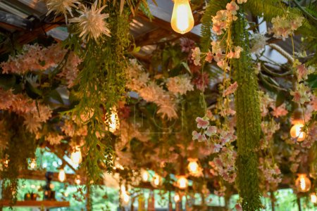 El techo está decorado con flores y plantas y bombillas cálidas Es una decoración interior natural para el diseño de una cafetería u oficina.