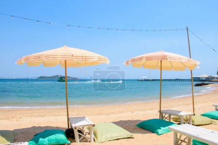 Bean bag chairs with tables and umbrellas on a beautiful white sand tropical beach on a summer vacation is a place for relaxation and water activities. Seaside seating on the beach.