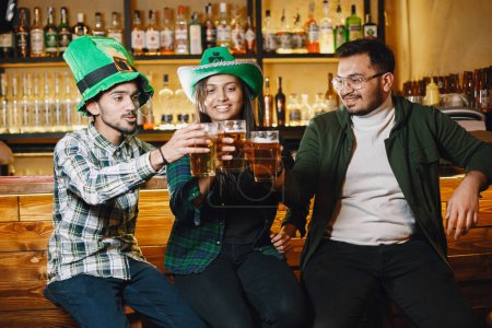 Guys and girl in green hats. Indians in a pub. St. Patricks Day celebration.