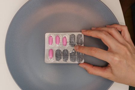 Foto de Aspectos esenciales del tratamiento farmacológico: Manos tocando parcialmente llena de ampolla de la píldora con geles suaves rosados - Imagen libre de derechos