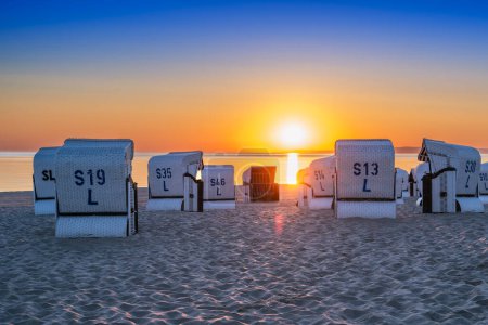 Foto de Salida del sol en la playa junto al mar Báltico con sillas de playa en la isla de Usedom - Imagen libre de derechos