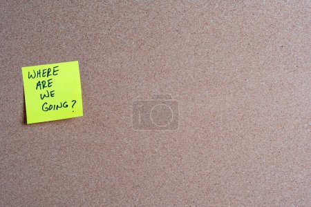 The words Where Are We Going on a yellow sticky note posted on a corkboard