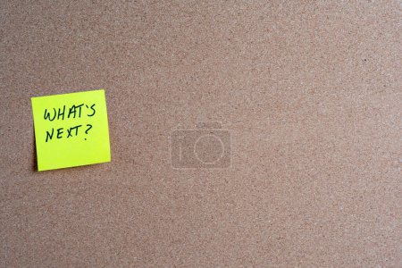 The words What's Next on a yellow sticky note posted on a corkboard