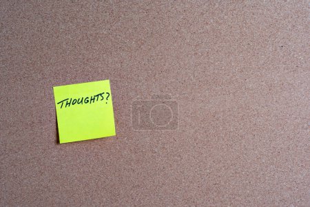 The word Thoughts on a yellow sticky note posted on a corkboard
