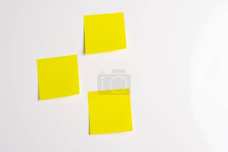 Three blank yellow sticky notes posted on an isolated white background