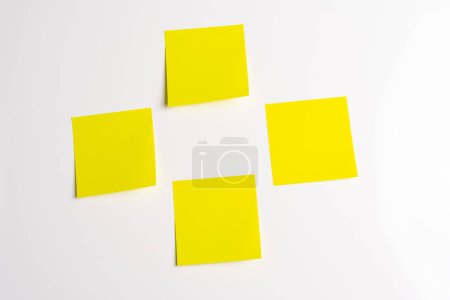 Four blank yellow sticky notes posted on an isolated white background