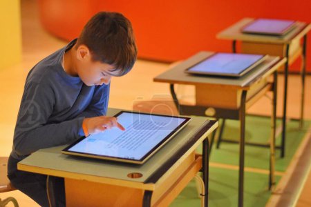 Foto de Niño jugando con una tableta en la biblioteca - Imagen libre de derechos