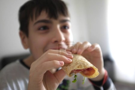 Photo for Boy eating a sandwich in his hand - Royalty Free Image
