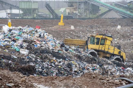 Foto de Vaciar residuos municipales. Trabajadores con camiones y excavadoras en el trabajo en vertederos de almacenamiento de residuos. - Imagen libre de derechos