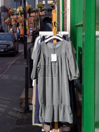 Téléchargez les photos : Robes suspendues à un rail devant le magasin de vêtements dans les rues de Manchester, dans Ancoats un après-midi ensoleillé. - en image libre de droit