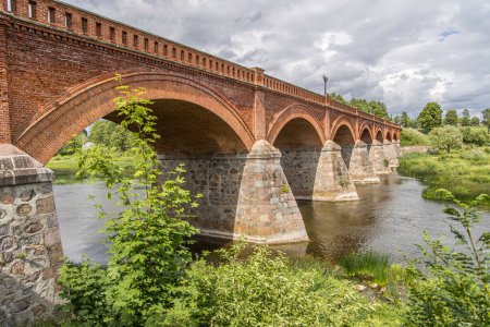 Photo for Kuldigas old brick bridge across the Venta river was built in 1874 and is the longest bridge of this kind of road bridge in Europe. Near it is the widest waterfall in the Baltics on the River Venta. - Royalty Free Image