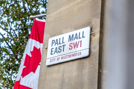 Photo for London, UK - September 14, 2023: Pall Mall East Street name sign on a Canadian embassy in Pall Mall East with Canadian Flags - Royalty Free Image