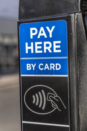 Recortado primer plano de la máquina de pago con tarjeta sin contacto al aire libre cerca de pey aquí signo.