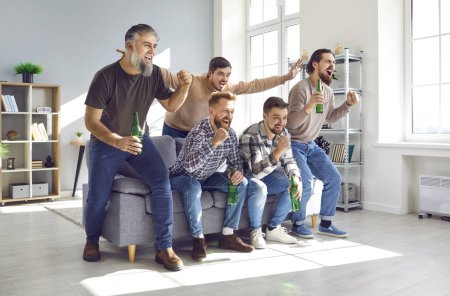 Photo for Happy friends watching soccer on tv and celebrating victory at home. Group of male football, soccer fans sitting on sofa with beer bottles and watching television. Male friendship, entertainment - Royalty Free Image