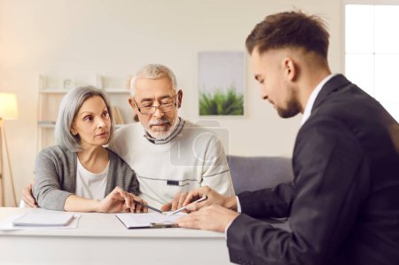 Elderly couple finalizes purchase of new property signing contract with realtor. Senior couple buying property signing contract in real estate agency Pensioners with realtor signing contract buying