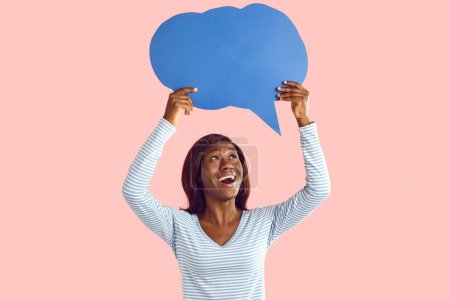 Photo for Happy excited young african american woman holding blank speech bubble for thoughts isolated on pink studio background. Girl with empty word cloud offering space for text. Idea concept. - Royalty Free Image
