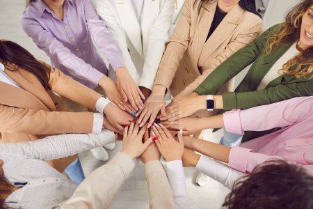Téléchargez les photos : Une équipe de jeunes femmes d'affaires multiraciales, diverses, debout dans un cercle et tenant leurs mains ensemble. Un angle élevé, tiré d'en haut. Travail d'équipe, pouvoir, soutien, unité, concepts de coopération - en image libre de droit