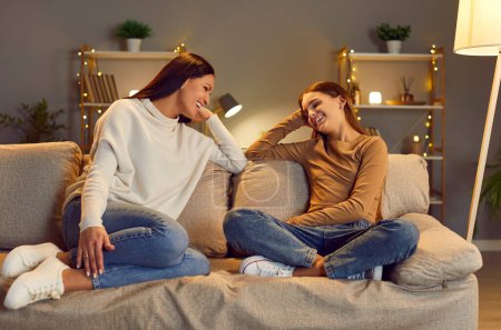 Photo for Happy mother and her teenage daughter spend time together at home and have cute conversation. Woman with teen girl sitting on sofa in cozy room, laughing while talking, showing strong family bond. - Royalty Free Image