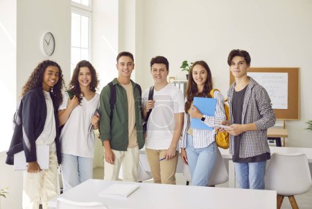 Photo for Diverse group of teenage students standing together in a school classroom. This snapshot captures the children unity and teamwork, where students from different backgrounds come together as one. - Royalty Free Image