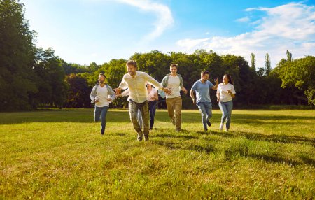Photo for Group of happy friends having fun in park on summer holidays. Several young people spending time in nature. Cheerful, joyful, excited men and women enjoying freedom and running on green grass in sun - Royalty Free Image