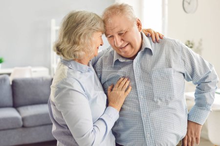 Téléchargez les photos : Heureux couple de la famille âgée embrassant à la maison, montrant l'amour et le bonheur. La femme et le mari sourient, profitant d'un moment ensemble à la maison, soulignant le lien fort et l'affection. - en image libre de droit
