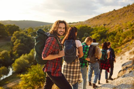 Téléchargez les photos : Portrait d'un randonneur heureux en groupe tricoté serré pendant un week-end de vacances, randonnée en montagne. Les sourires reflètent la joie partagée par les amis ou l'équipe de touristes, créant une marche positive dans la nature. - en image libre de droit