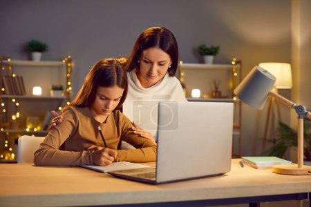 Mother and young daughter witting task, letter near laptop, family in love, happy motherhood emotion. Parent and teen receives education at home, enjoy time together in good mood, e-learning course