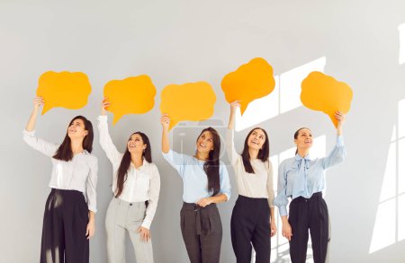 Photo for Happy girls, young female group of business people, friends holding empty paper speech bubbles, representing talk. Women thought bubble, thinking dialogue balloon, idea, plan, sharing opinion, belief - Royalty Free Image