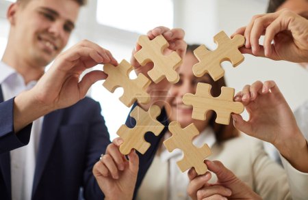 Photo for Close up of hands of a business team holding puzzle pieces in the office. Work company conveying teamwork and communication, each hand contributing a unique piece to the group vision. - Royalty Free Image