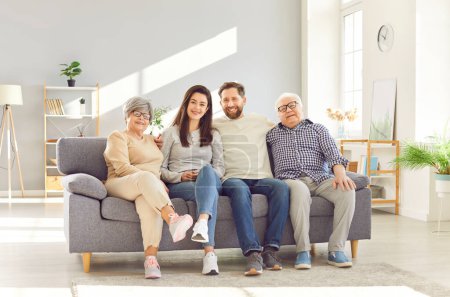 Big family old parents adult children seated side by side on sofa looking at camera laughing and smiling. Big happy family moments together family happiness love joy and happy smiling