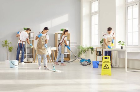 Photo for Cleaner group working, happy workers with tools, professional janitor service busy cleaning home, office. Young people take care of room, small company maintaining washing, dusting, mopping, vacuuming - Royalty Free Image