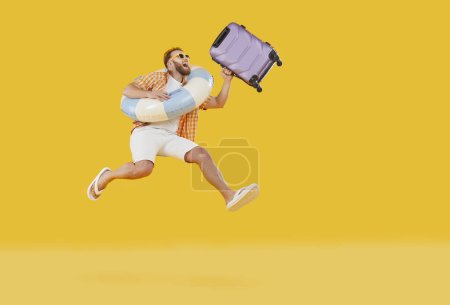 Happy tourist man in holiday beach wear holding large wheel suitcase bag, swimming ring running for summer trip. Male tourist dreaming of leisure, recreation, travelling, happy to enjoy rest, emotions