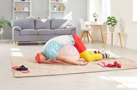 Photo for Lazy or tired funny man wearing retro sportswear is sleeping on the floor during a home workout training. His humorous approach to fitness is evident in nap during gym time at home. - Royalty Free Image
