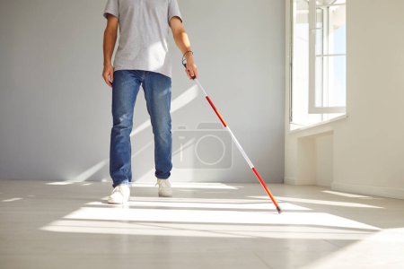 Retrato de sección media de un hombre ciego en casa, utilizando un bastón para mejorar la movilidad. Esta imagen refleja la búsqueda de la accesibilidad y destaca la importancia de la salud y la independencia.