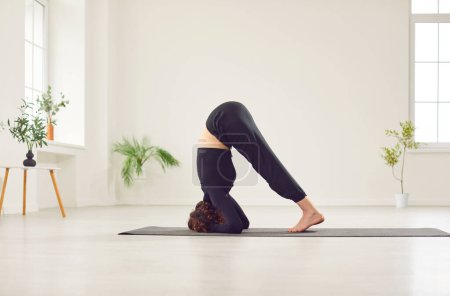 Téléchargez les photos : Femme pratique le yoga, effectuer un asana pour s'étirer pendant son entraînement de gymnastique. Elle fait preuve de souplesse et de concentration, combinant yoga et fitness pour un entraînement sportif équilibré. - en image libre de droit