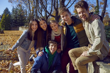 Foto de Retrato de un grupo de amigos felices caminando en el parque de otoño. Jóvenes caucásicos niñas y niños mirando a la cámara y sonriendo alegremente al aire libre. Concepto de amistad y unión. - Imagen libre de derechos