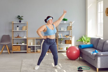 Overweight, obese woman doing physical exercises indoors at home. Plus size, fat young woman in sportswear and headband doing various sport exercises. Sport, weight loss, healthy lifestyle