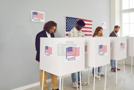 Portrait of a group of young confident diverse American citizens people men and women standing at vote center with USA flags in voting booth putting their ballots in bin on election day.