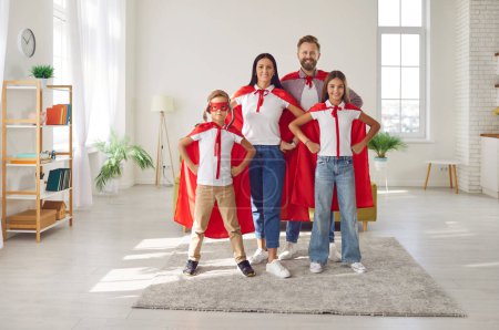 Photo for Full length portrait of a cheerful family dressed in colorful superhero costumes at home living room, the parents and children radiate infectious smiles, embodying strength, fun, and unity. - Royalty Free Image