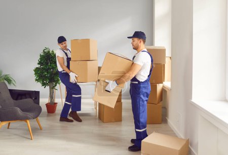 Photo for Workers from the delivery company transport belongings to a new house or apartment. Two men from the moving service carry lots of cardboard boxes and other stuff for people who are relocating - Royalty Free Image