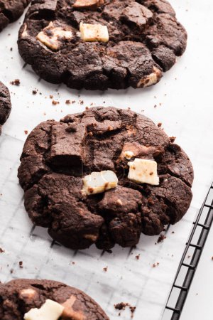 Photo for A vertical closeup shot of multiple dark chocolate cookies on baking paper - Royalty Free Image