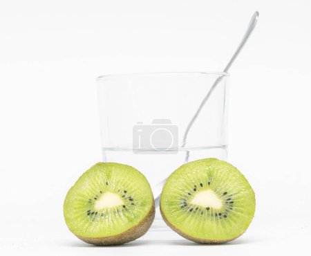Photo for Explore the vibrant world of healthy eating with our stunning photograph of two ripe kiwis in sharp focus, set against a beautifully blurred background featuring a glass of water and a fork. Perfect for promoting a nutritious lifestyle, this image is - Royalty Free Image