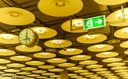 Téléchargez les photos : Capturez l'essence du voyage avec notre fascinante photo de stock de l'emblématique terminal 4 de l'aéroport de Barajas à Madrid, en Espagne. Cette image présente un plafond à couper le souffle orné d'élégants luminaires, une horloge bien en vue et un panneau de départ. Élévation - en image libre de droit