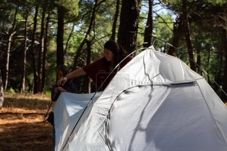Photo for Family Bonding: Mother and Son Pitching a Tent in the Woods - Royalty Free Image
