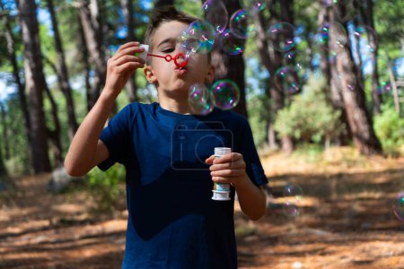 Photo for Boy in nature blowing to make lots of soap bubbles - Royalty Free Image