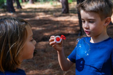 Photo for Two children in the woods playing with soap bubbles - Royalty Free Image