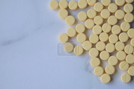 de nombreuses pilules jaunes sur une table blanche vue d'en haut