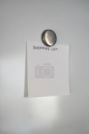 Empty shopping list stuck with a magnet on the white fridge