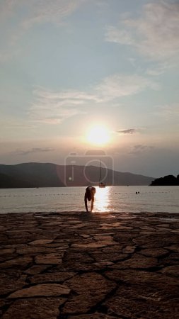 Photo for Silhouette of man throwing himself headlong into the sea in a sunset - Royalty Free Image